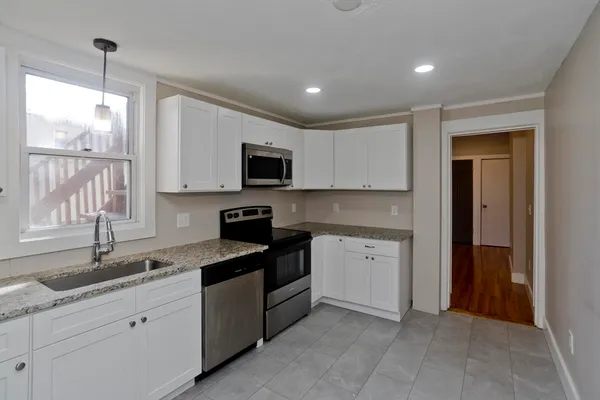 a kitchen with granite countertop white cabinets stainless steel appliances a window and a sink