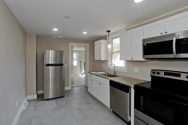 a large kitchen with stainless steel appliances granite countertop a refrigerator and a stove top oven