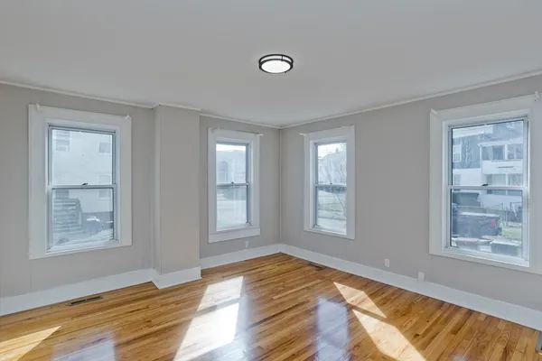 a view of an empty room with window and wooden floor