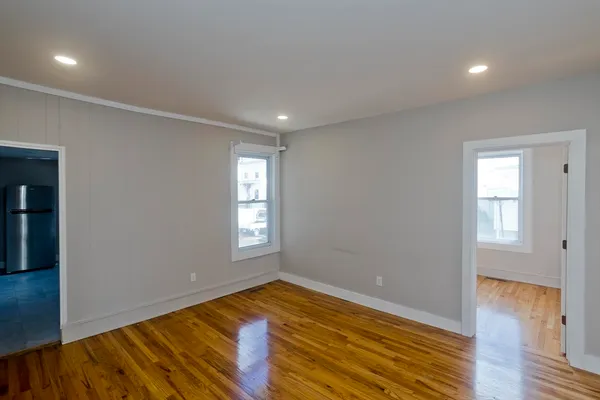 a view of empty room with wooden floor and fan