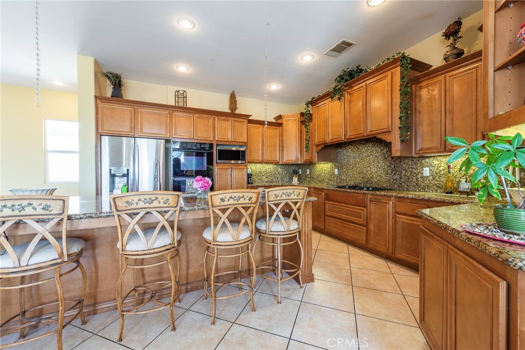 10281 Hillside Road Rancho Cucamonga, CA 91737 - Photo 26 of 60 a kitchen with stainless steel appliances granite countertop table chairs sink and cabinets