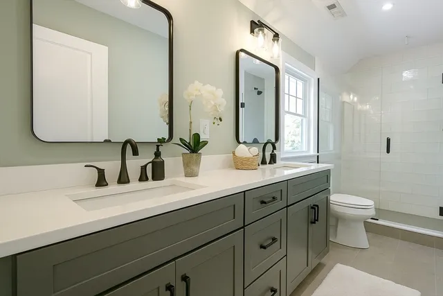 a bathroom with a double vanity sink toilet and mirror