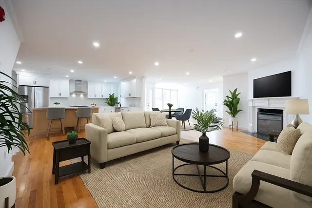 a living room with furniture a fireplace a flat screen tv and a potted plant