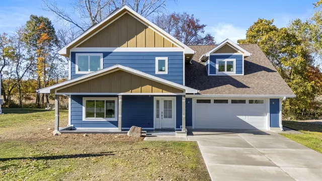 a view of a house with a yard plants and large tree