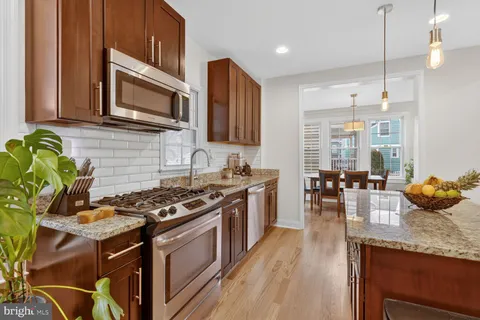 a kitchen with stainless steel appliances granite countertop a stove a sink dishwasher and microwave with wooden floor