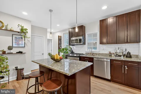 a kitchen with granite countertop kitchen island stainless steel appliances a sink stove and cabinets