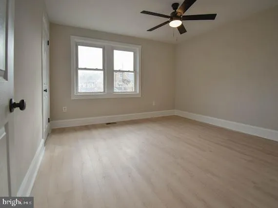 a view of an empty room with wooden floor and a kitchen
