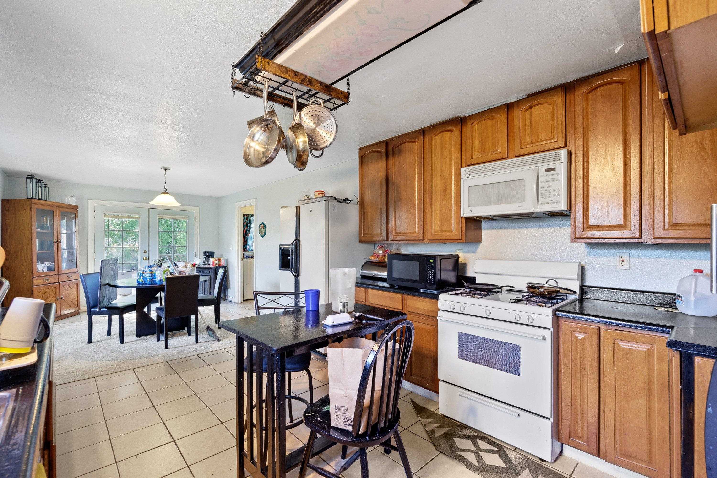1220 5th Avenue Corning, CA 96021 - Photo 6 of 15 a kitchen with stainless steel appliances granite countertop a stove a refrigerator a dining table and chairs with wooden floor