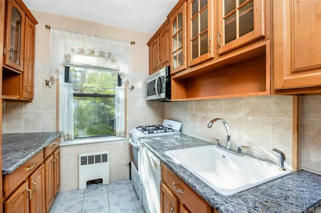 a kitchen with stainless steel appliances granite countertop a sink a stove and a wooden cabinets