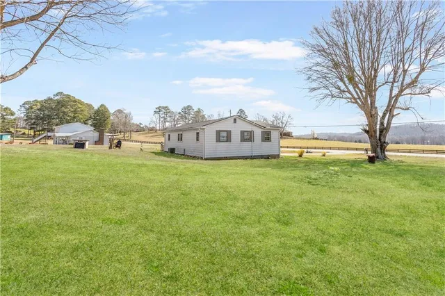 a view of a house with a big yard and large trees
