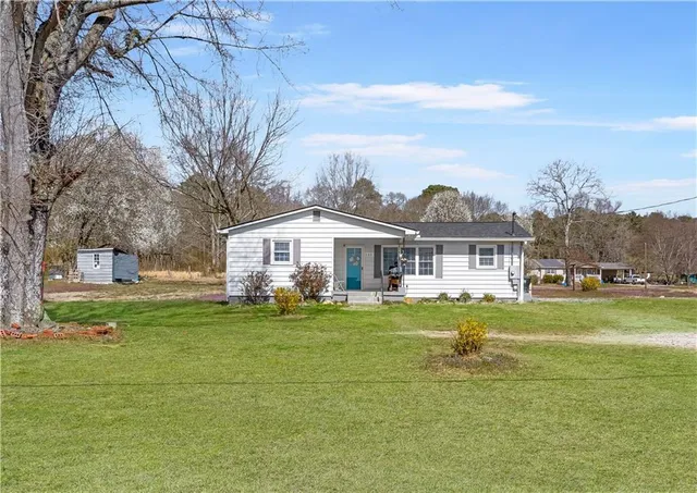 a front view of a house with a garden and trees