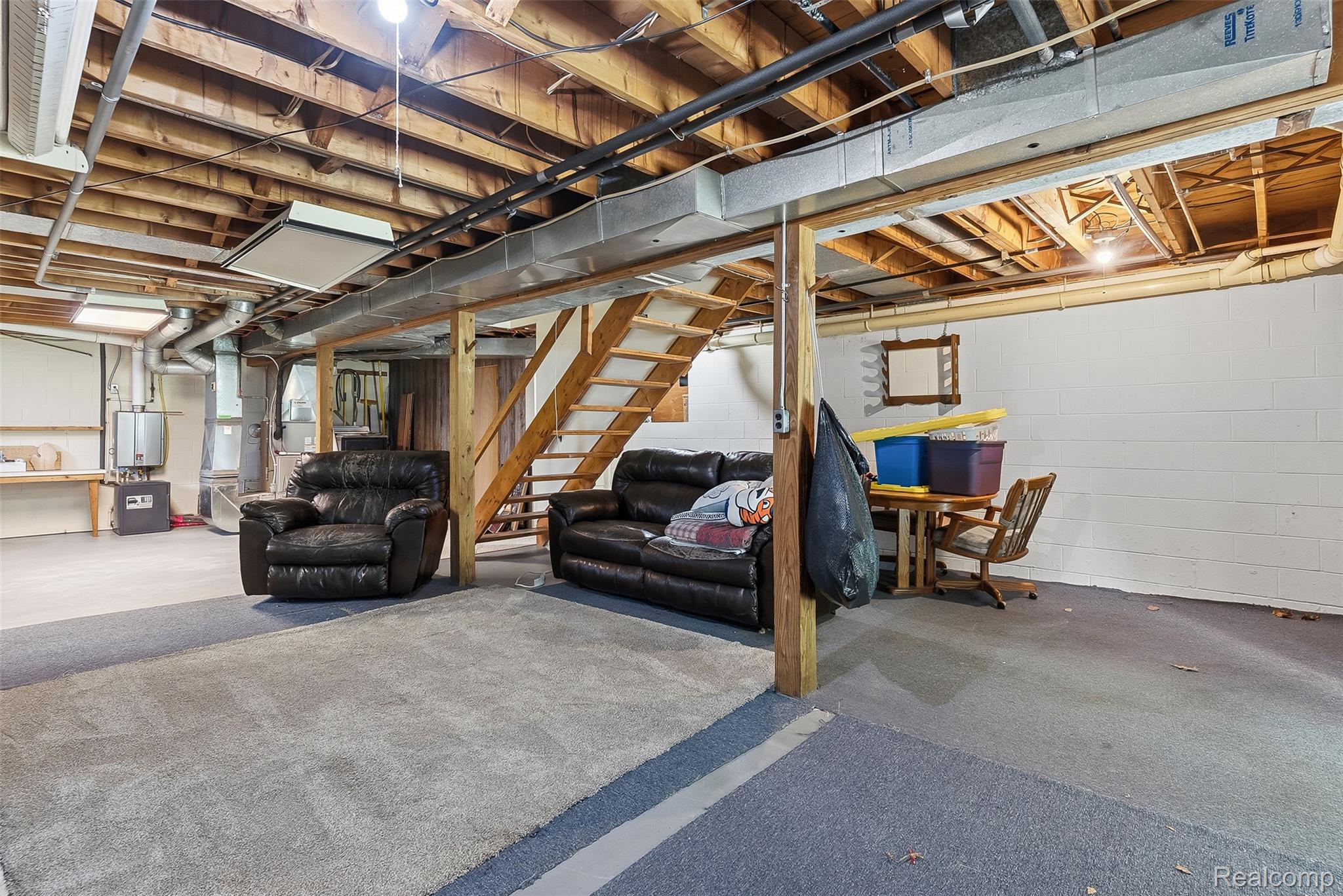 3656 Stanley Road Columbiaville, MI 48421 - Photo 33 of 65 Open basement space with exposed wood beam ceiling, painted block walls, and mixed flooring including carpeting and concrete