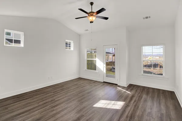 a view of an empty room with window and wooden floor