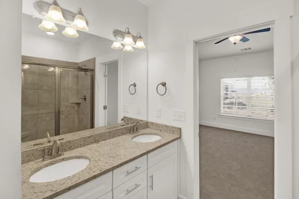 a bathroom with a granite countertop sink a large mirror and a shower