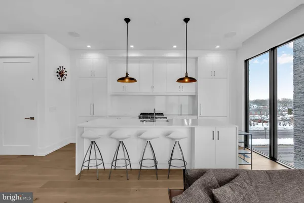 a kitchen with stainless steel appliances a stove a refrigerator a sink and white cabinets with wooden floor