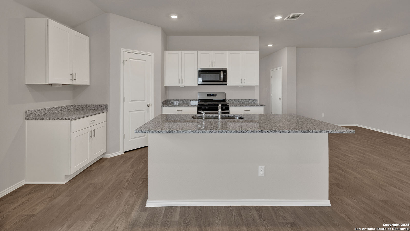 322 Hodges Street Maxwell, TX 78656 - Photo 15 of 34 a large kitchen with granite countertop a stove top oven a sink dishwasher and white cabinets with wooden floor