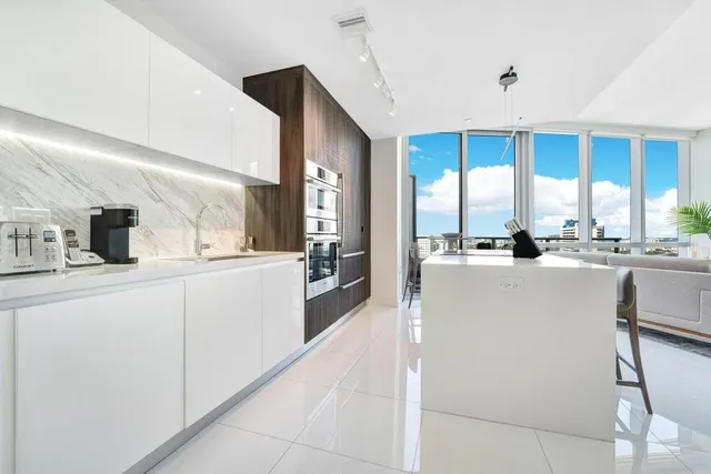 a large white kitchen with kitchen island a sink a stove and a refrigerator