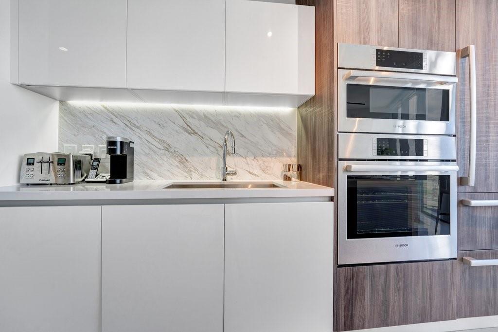851 Northeast 1st Avenue, Unit 2202 Miami, FL 33132 - Photo 6 of 56 a kitchen with granite countertop white cabinets and stainless steel appliances