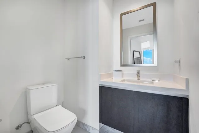 a bathroom with a toilet a sink a mirror and vanity