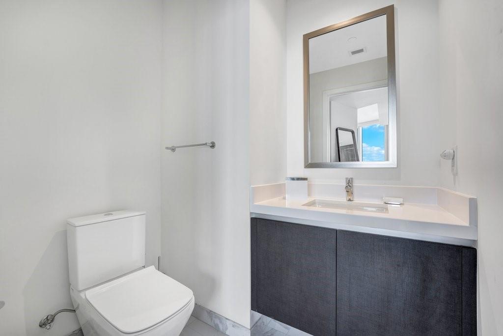 851 Northeast 1st Avenue, Unit 2202 Miami, FL 33132 - Photo 10 of 56 a bathroom with a toilet a sink a mirror and vanity