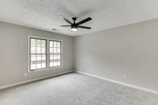 an empty room with a window and a fan