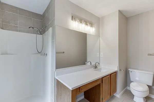 a bathroom with a granite countertop sink a toilet and shower