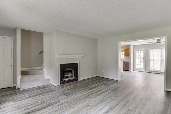 an empty room with wooden floor fireplace and windows