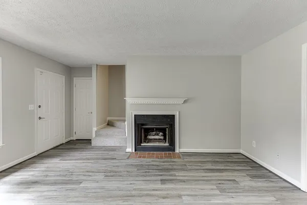 a view of a livingroom with wooden floor and a fireplace