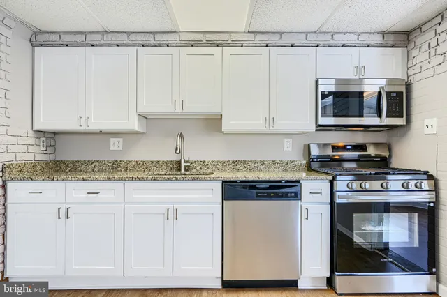 a kitchen with granite countertop white cabinets and stainless steel appliances