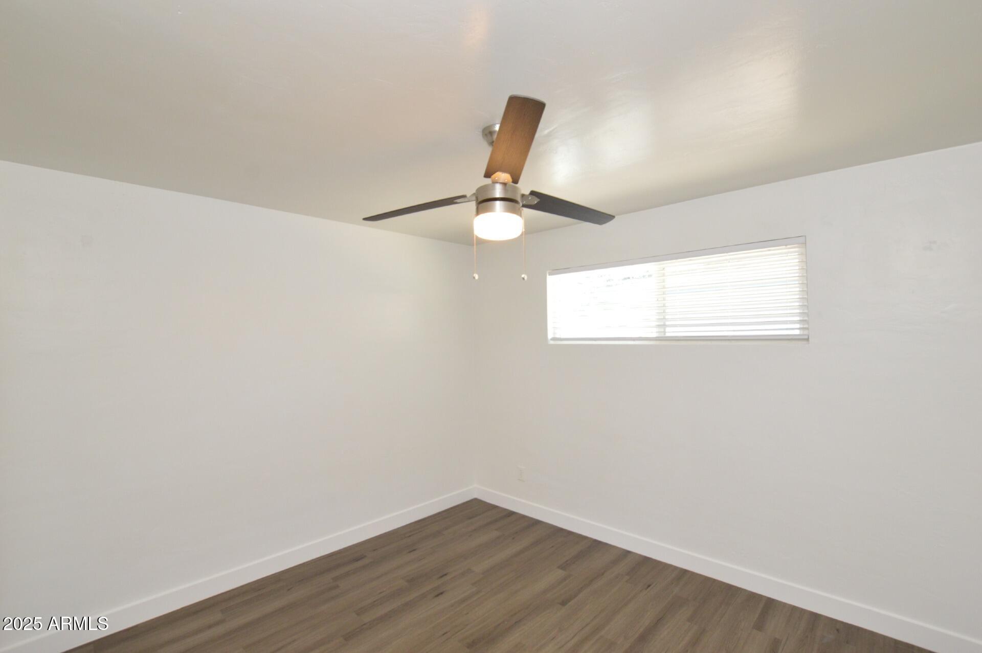 1202 East Kaler Drive, Unit 1 Phoenix, AZ 85020 - Photo 12 of 16 an empty room with wooden floor fan and window