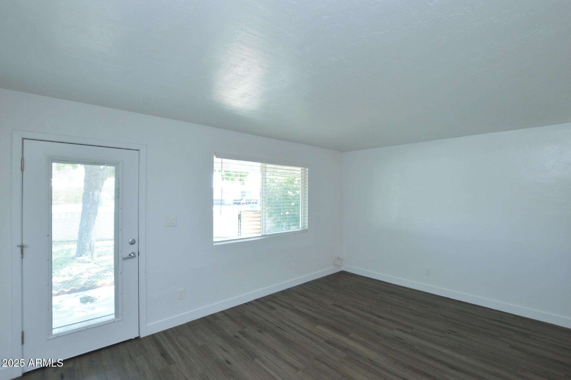 1202 East Kaler Drive, Unit 1 Phoenix, AZ 85020 - Photo 6 of 16 an empty room with wooden floor and windows