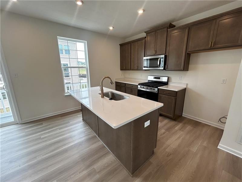 118 Affinity Drive Harmony, PA 16037 - Photo 4 of 8 a kitchen with stainless steel appliances a stove a sink a microwave and wooden cabinets