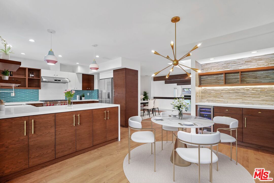 1569 Michael Lane Pacific Palisades, CA 90272 - Photo 14 of 31 a large kitchen with stainless steel appliances kitchen island granite countertop a table chairs in it and a window