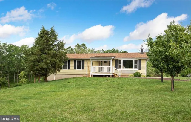 a white house with a big yard and large trees
