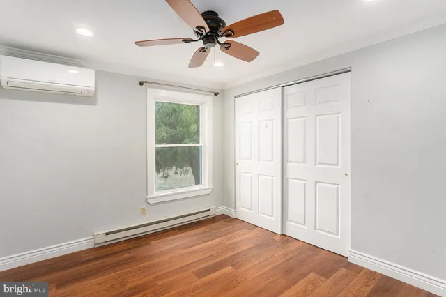 an empty room with wooden floor chandelier fan and windows