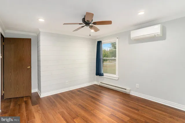 a view of empty room with wooden floor and fan