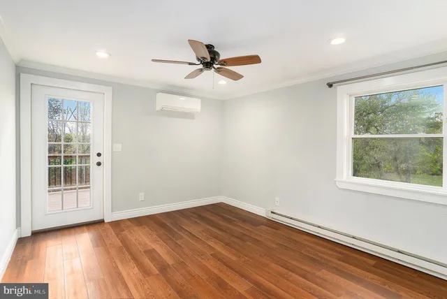an empty room with wooden floor fan and windows