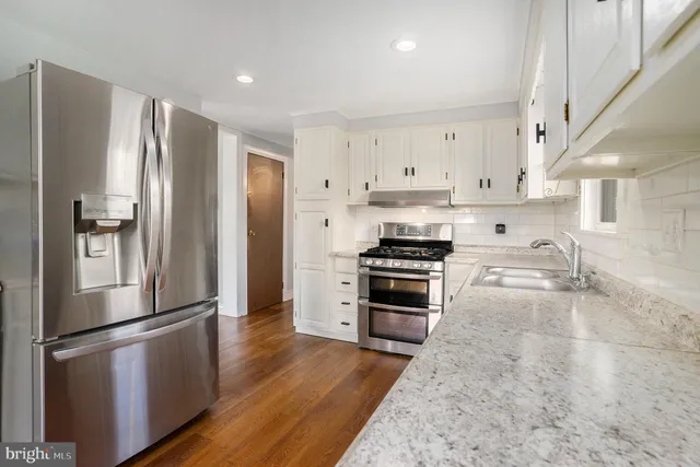a kitchen with granite countertop a refrigerator and a stove top oven