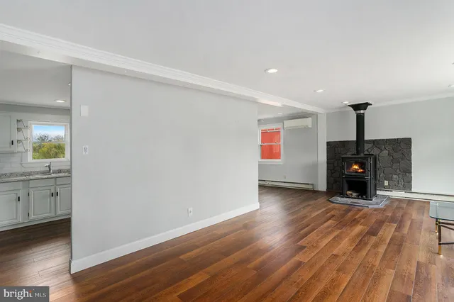 a view of an empty room with wooden floor a fireplace and a window