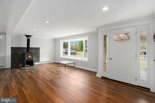 an empty room with wooden floor fireplace and windows