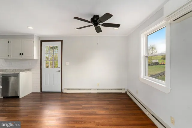 an empty room with wooden floor a ceiling fan and windows