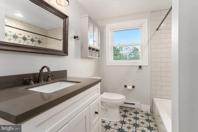 a bathroom with a granite countertop toilet a sink and a mirror