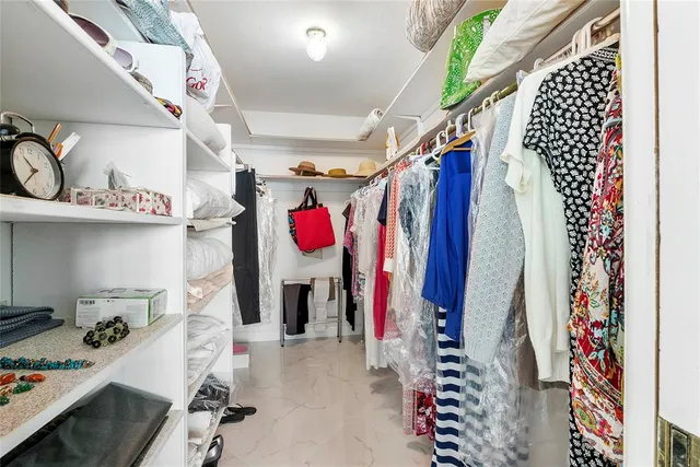 a view of walk in closet with clothes and shoes