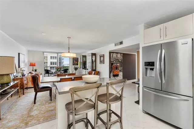 a living room with stainless steel appliances furniture and a kitchen view