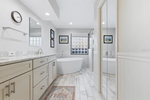 a bathroom with a granite countertop sink mirror and a bathtub