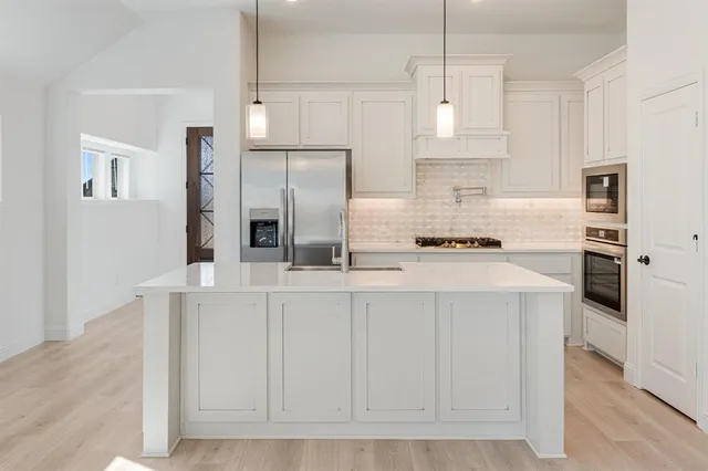 a kitchen with stainless steel appliances granite countertop a stove a sink and a refrigerator