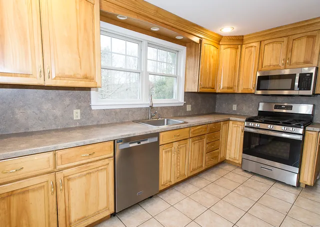 a kitchen with granite countertop white cabinets stainless steel appliances a sink and a window