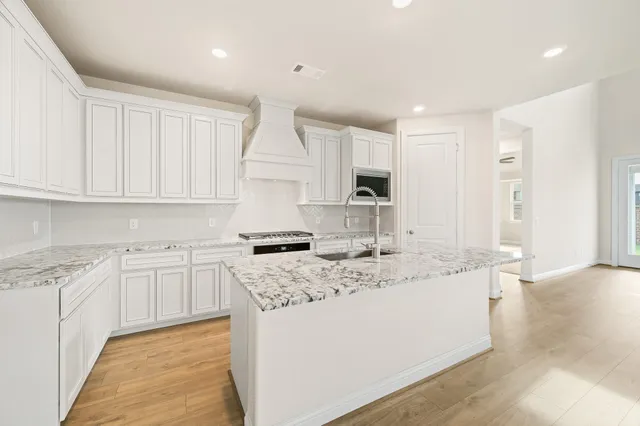 a kitchen with granite countertop a sink a stove a refrigerator and white cabinets