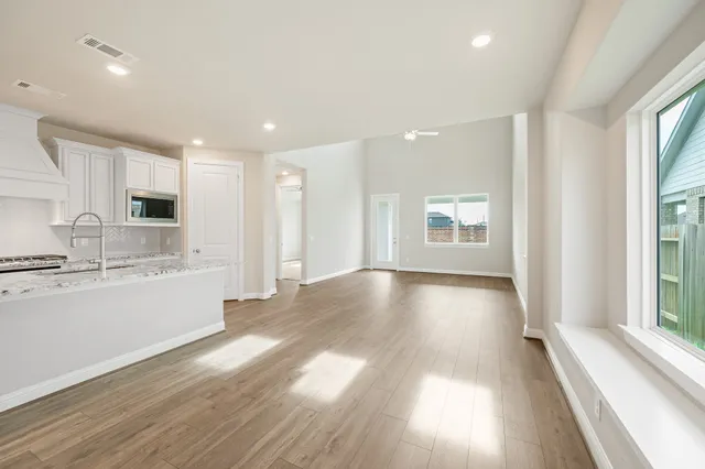 a view of an empty room with window and wooden floor