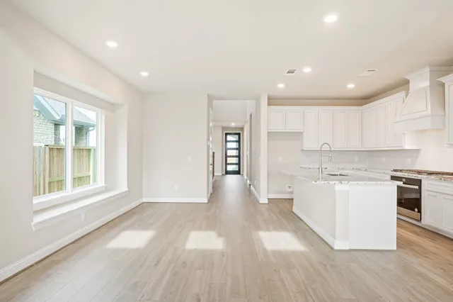 a view of a kitchen with kitchen island a sink wooden floor and a large window